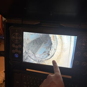 מסך עם תמונה של צינור חלוד, יד מצביעה על המסך