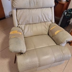 כורסה עם ריפוד בלוי וקרעים בידיות