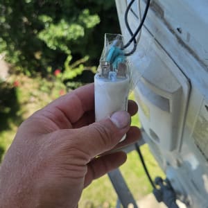 יד מחזיקה רכיב חשמלי ליד מזגן חיצוני