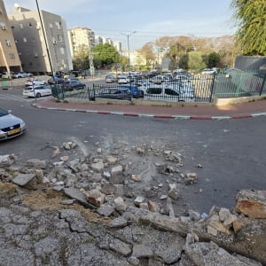 אבנים שבורות על המדרכה ליד כביש ומכוניות