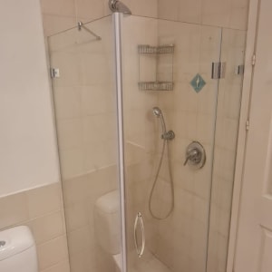 מקלחון זכוכית עם ראש מקלחת ומדף מתכת