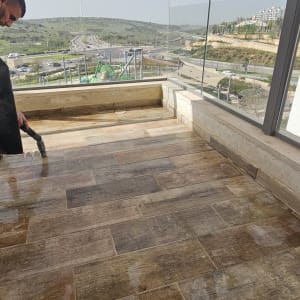 אדם מנקה מרפסת עם רצפת עץ ונוף פתוח