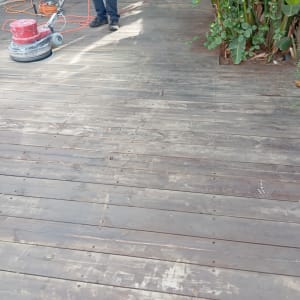 אדם משייף דק עץ עם מכונת ליטוש אדומה