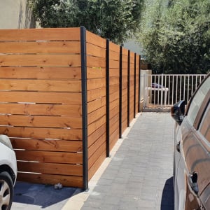 גדר עץ חומה עם עמודי מתכת שחורים