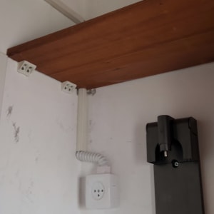 שקע חשמל עם כבל מסולסל על קיר לבן