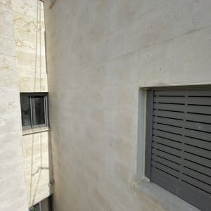 קיר אבן עם חלון ותריס אפור