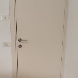 דלת לבנה עם ידית מתכת ומתגי חשמל