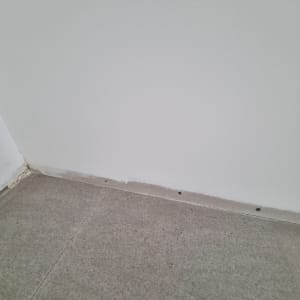 קיר גבס עם חורים קטנים ליד הרצפה