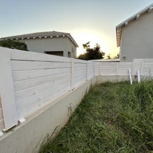 גדר עץ לבנה בחצר עם דשא ירוק