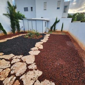 שביל אבנים בגינה עם צמחים וקרקע אדומה