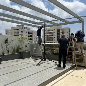 עובדים מתקינים פרגולה מאלומיניום על גג בניין
