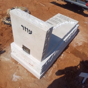 מצבה חדשה על אדמה עם רכב ברקע