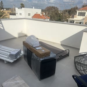 חפצים ארוזים על מרפסת, כולל קרטונים ואריזות פלסטיק