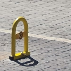 מחסום חניה צהוב על מדרכה מרוצפת
