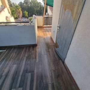 מרפסת עם דלת מתכת, רצפת עץ וכלי איטום על המעקה