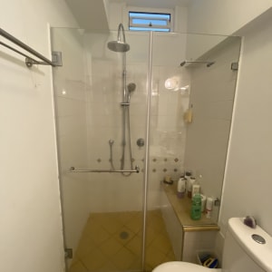 מקלחת עם דלת זכוכית ומוצרים על מדף