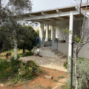 פרגולה מעץ בכניסה לבית עם גינה קטנה