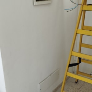 ארון חשמל פתוח, סולם צהוב, תיק כלים עם מברגים