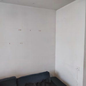 קיר לבן עם חורים קטנים וספה כחולה