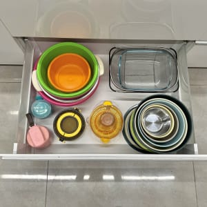 קערות צבעוניות ומיכלים מסודרים במגירה במטבח