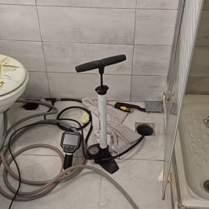 כלים וכלים בחדר אמבטיה, כולל משאבה וצינורות.