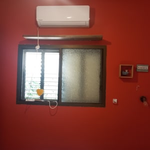 קיר צבוע באדום עם חלון ומזגן