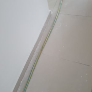 רצפה עם כתמי צבע וכבל חשמל לאורך הקיר