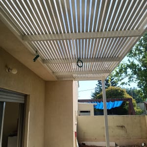 פרגולה לבנה עם קורות עץ בחצר