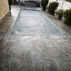בריכה מכוסה עם רצפת אבן מסביב וצמחייה