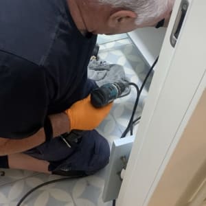 אדם עם מקדחה חשמלית ליד כיור