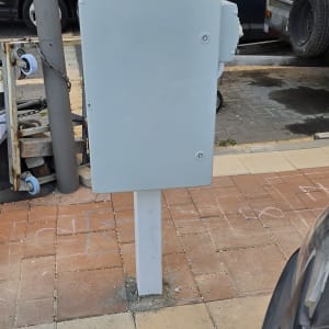 ארון חשמל מותקן על מדרכה ליד מכוניות