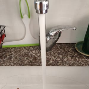 ברז מים זורם בכיור מטבח עם קרש חיתוך