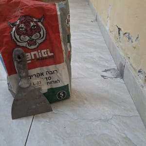 שק מלט ומרית על רצפה ליד קיר מתקלף