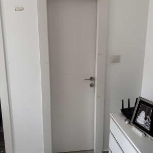 דלת לבנה עם ידית מתכת, מסגרת מודבקת בנייר דבק