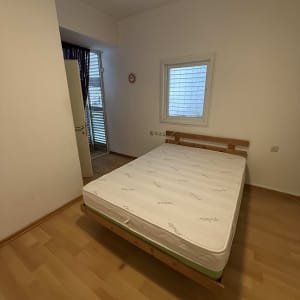 חדר שינה עם מיטה ומזרן על רצפת עץ