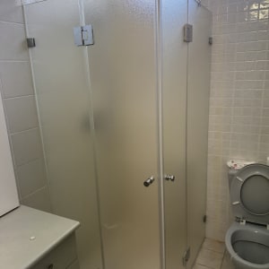 תא מקלחת מזכוכית בחדר אמבטיה עם שירותים