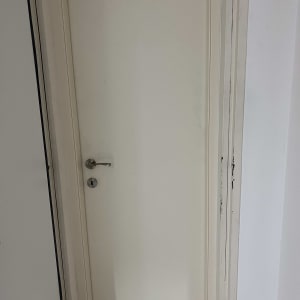 דלת לבנה עם ידית מתכת כסופה ומנעול