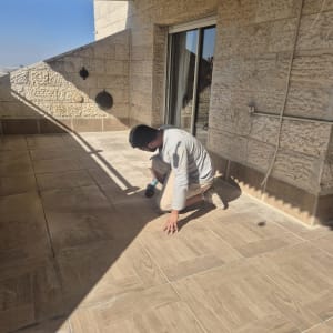 אדם עובד על רצפת מרפסת עם כלי עבודה
