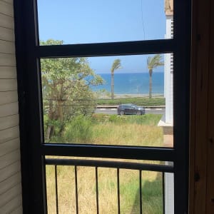 חלון אלומיניום עם נוף לים ועצים