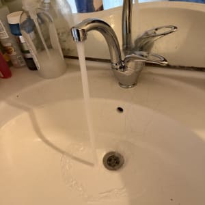 ברז מים זורם בכיור עם סבון ומוצרי ניקוי