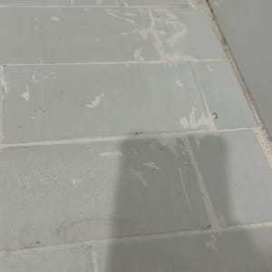 תמונת תקריב של אריחי ריצוף בחדר רחצה עם שאריות רובה או צבע