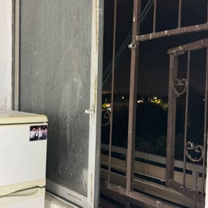 חלון פתוח עם סורג ליד מקרר, לא מציג עבודה בתחום.