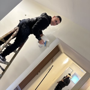 אדם צובע קיר עם מברשת על סולם