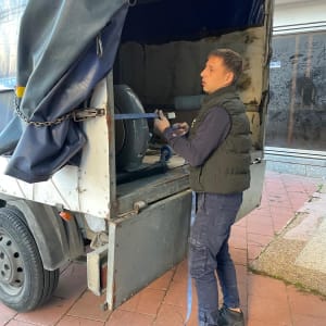 אדם מחבר רצועה למשאית פתוחה עם ציוד בפנים