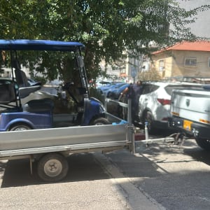 רכב גרירה עם עגלה חונה ברחוב ליד עצים