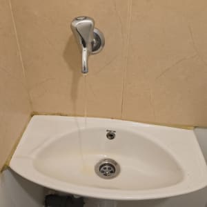 כיור עם ברז מים זורמים על קיר קרמיקה
