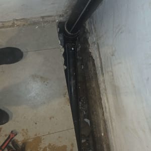 צינור מותקן בפינת קיר עם כלים על הרצפה