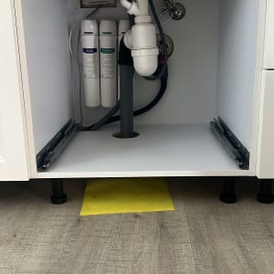 כיור עם צנרת ומסננים מתחת לארון מטבח