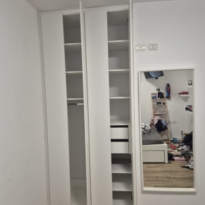 ארון בגדים לבן עם מדפים ודלתות פתוחות