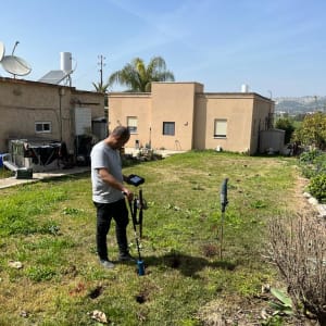 אדם משתמש בגלאי דליפות על דשא בחצר